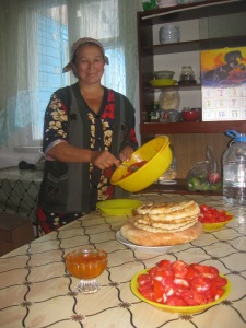 Gula, Samat's mother, serving bread, apricot jam, and tomato salad in our kitchen